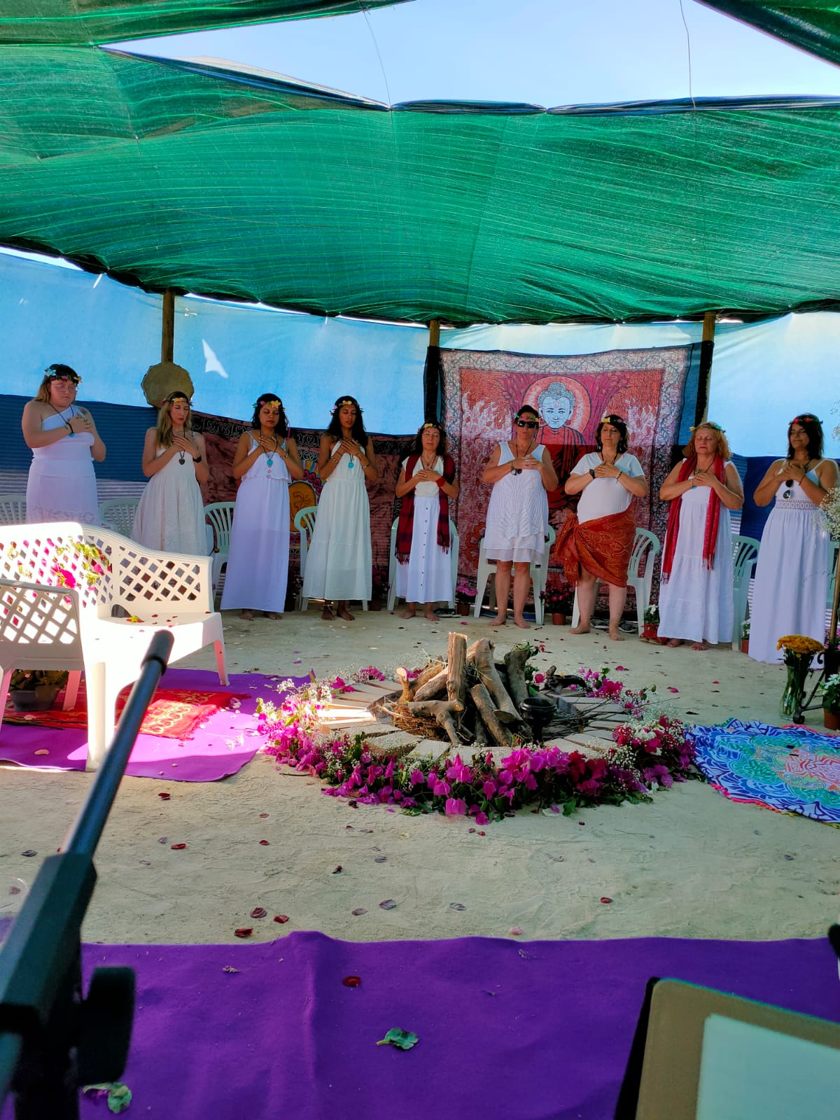Ceremonia de fuego con círculo de flores y participantes vestidas de blanco